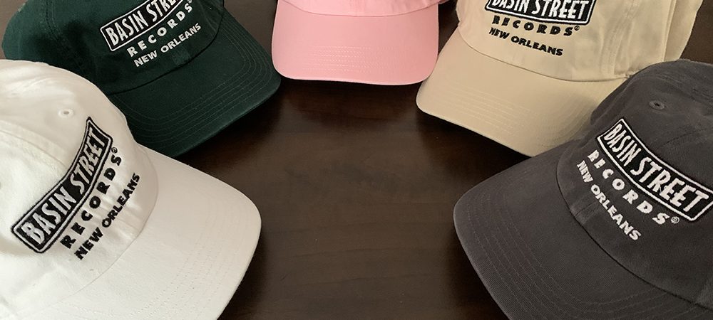 Five hats in five different colors—white, dark green, pink, stone, and grey, all embroidered with the Basin Street Records logo in black