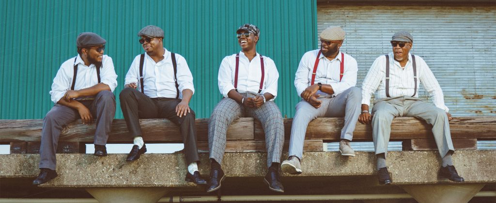 A press photo of Kevin & The Blues Groovers sititng on the edge of a dock