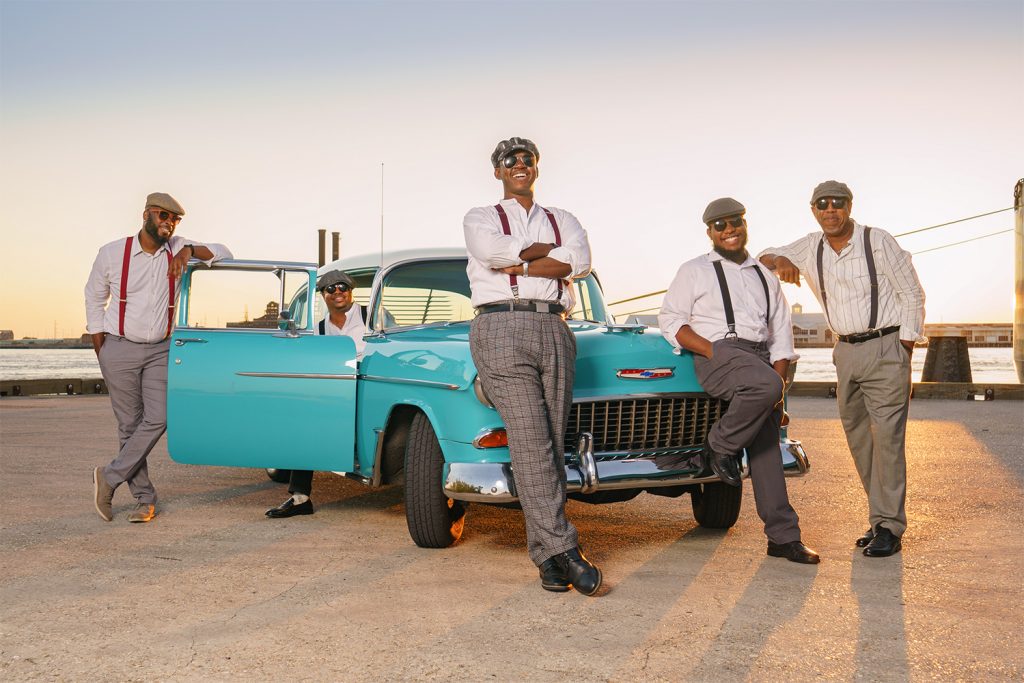 Press photo of Kevin & The Blues Groovers standing in front of a teal vintage Chevrolet